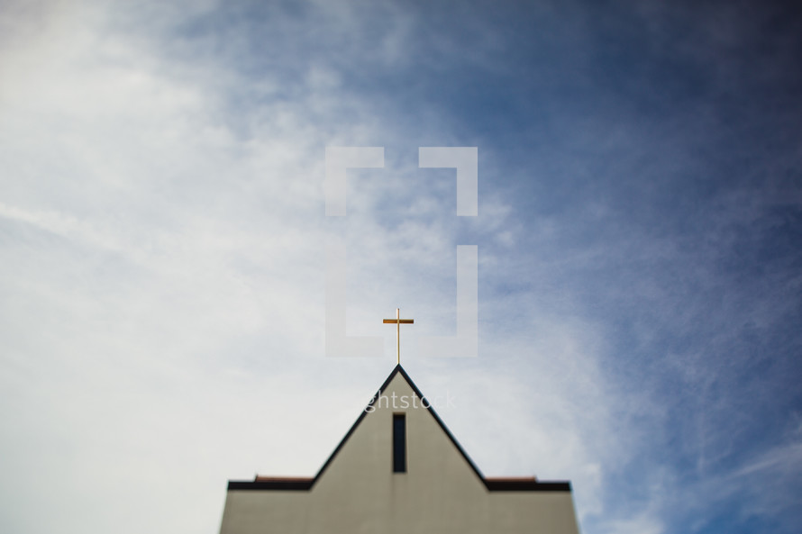Steeple of a church with a cross in the sky.