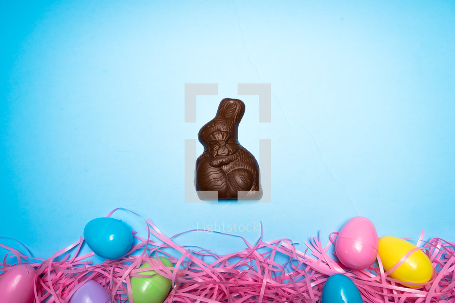 Chocolate Easter rabbit and Easter eggs over a blue background 