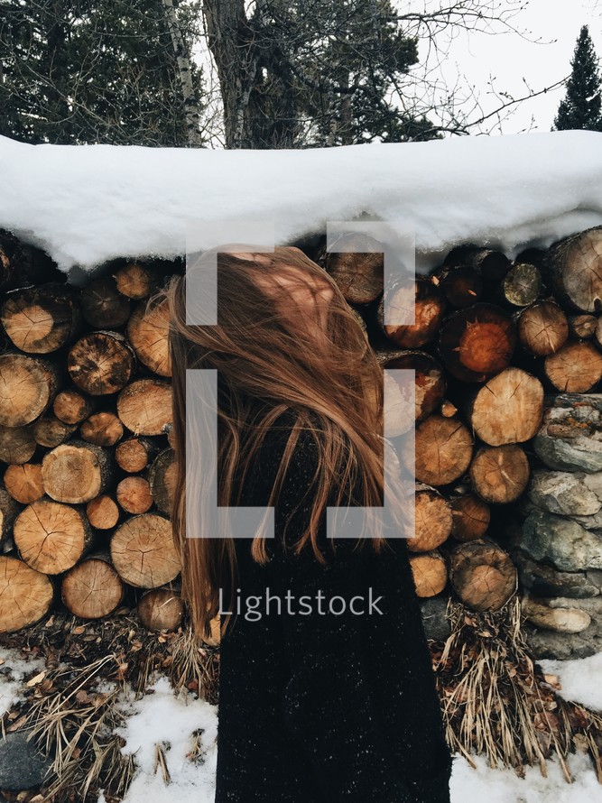 woman and snow on a pile of logs 