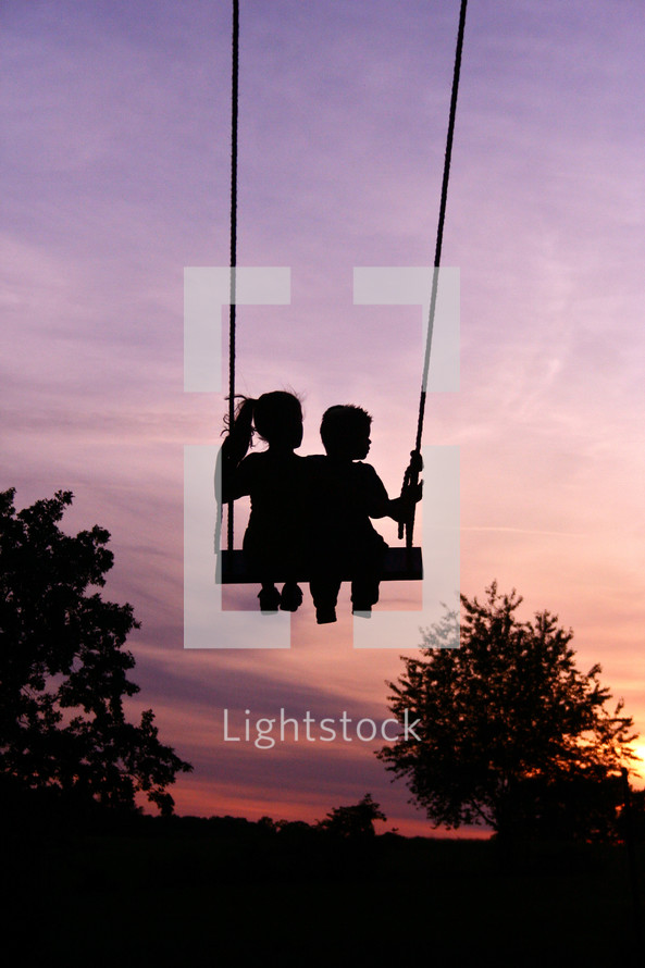 silhouettes of children on a swing 