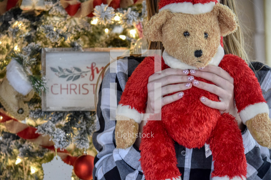 female child holding a Santa Claus Teddy Bear gift for Christmas 