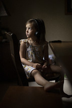 a girl listening to headphones sitting at a table 