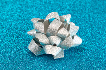 silver bow on blue glittery background 