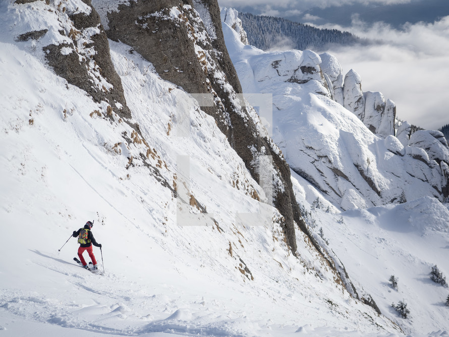 Lonely free-rider skier in high mountains. Extreme freestyle skiing in sunny daylight on winter mountain landscape