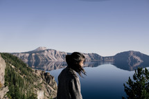 woman standing in front of a mountain lake