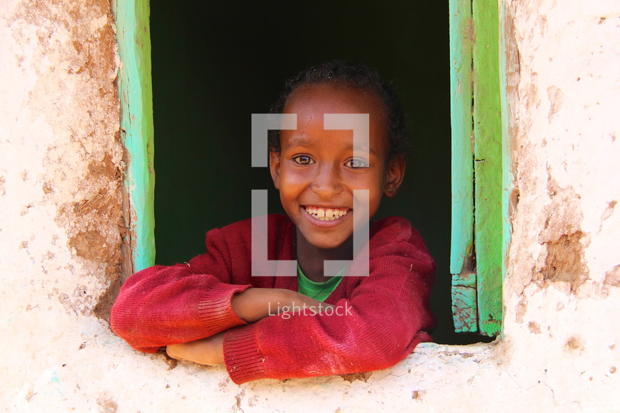Young Ethiopian child smiling from a window 