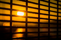 sun at sunset through metal bars 