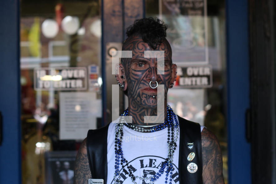 A tattooed man with a mohawk and nose ring.