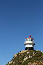 Lighthouse on a hilltop against a blue sky.