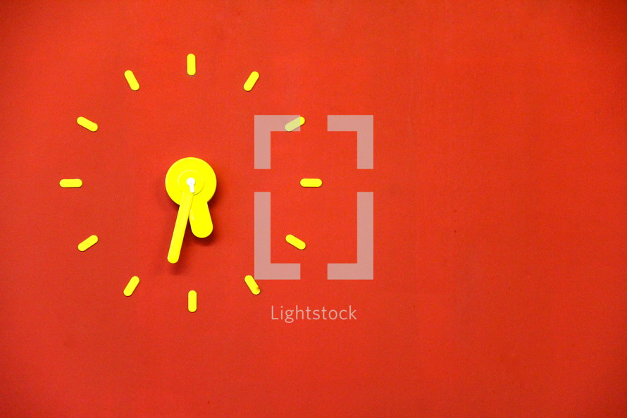 Yellow hands of a clock on a red background 