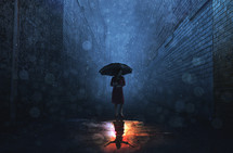 rain falling on a woman holding an umbrella at night 