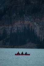 paddling a canoe on a lake  in front of a mountain 