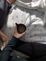 a woman sitting in a bed with a cup of coffee 