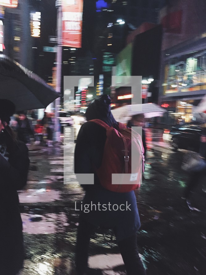 people on a crosswalk in NYC on a rainy night 
