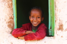 Young Ethiopian child smiling from a window 