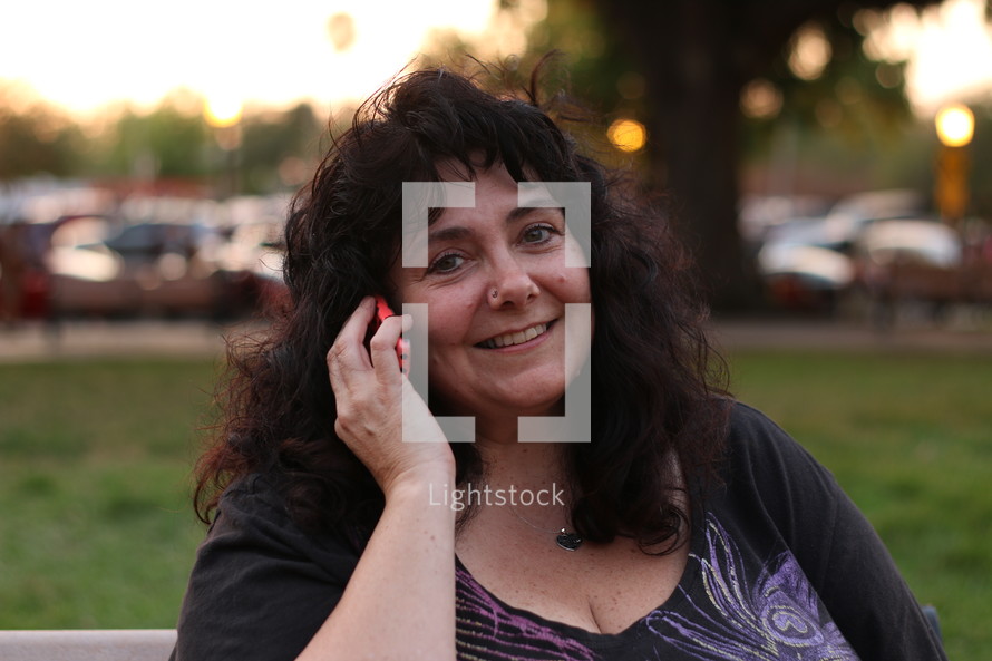 A smiling woman talking outside on a cell phone.