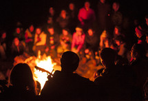 large group gathered around a camp fire 
