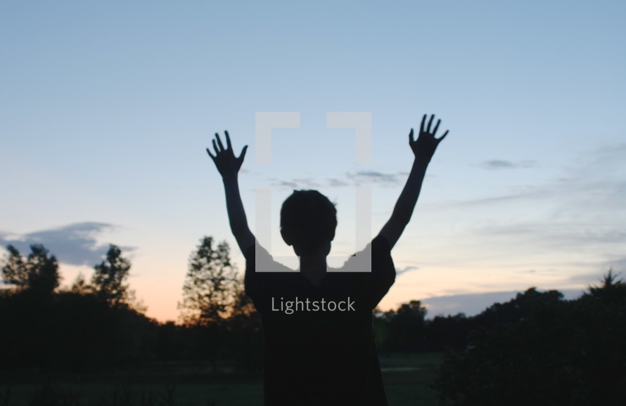 silhouette of a boy with his hands raised 