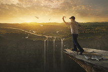 a man throwing paper airplanes off the edge of a cliff 