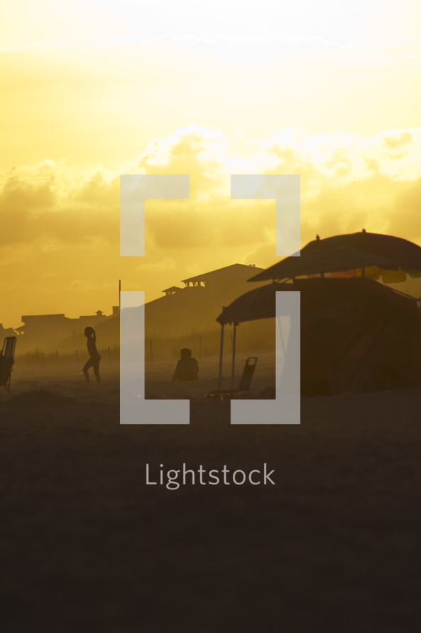 tents on a beach under the glow of the sun at sunset 