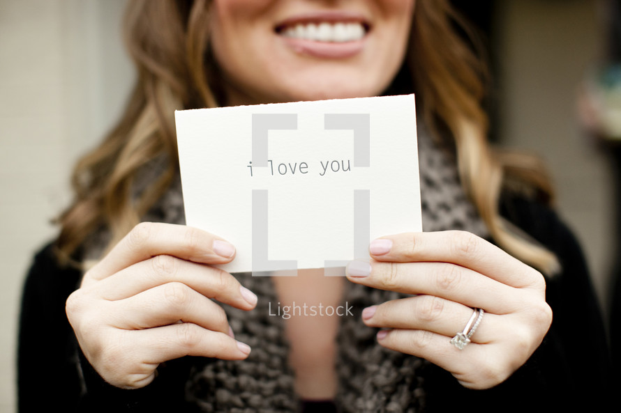 woman holding a notecard with the words I Love You 