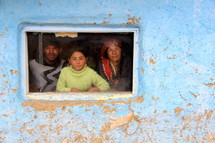 A Romanian Gypsey family looking through a window in their home