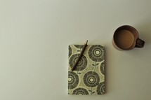 pencil on a journal and coffee mug 