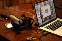 Syncing video camera with a laptop on a wood desk.