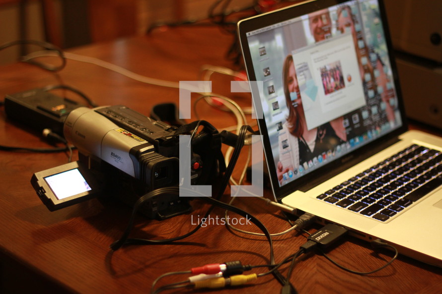 Syncing video camera with a laptop on a wood desk.
