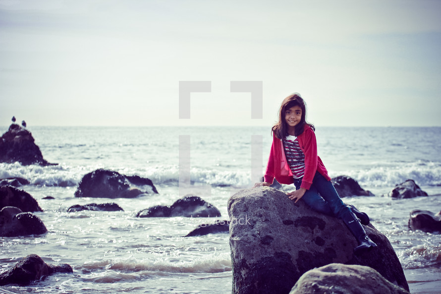 girl child on a rock at the beach 