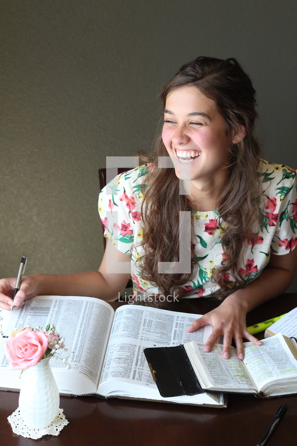 A laughing girl studying the Bible.