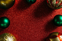 Christmas ornaments border on a red glittery background 