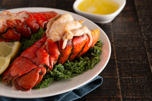 two Broiled Lobster Tails on a Bed of Kale with Lemon Slices