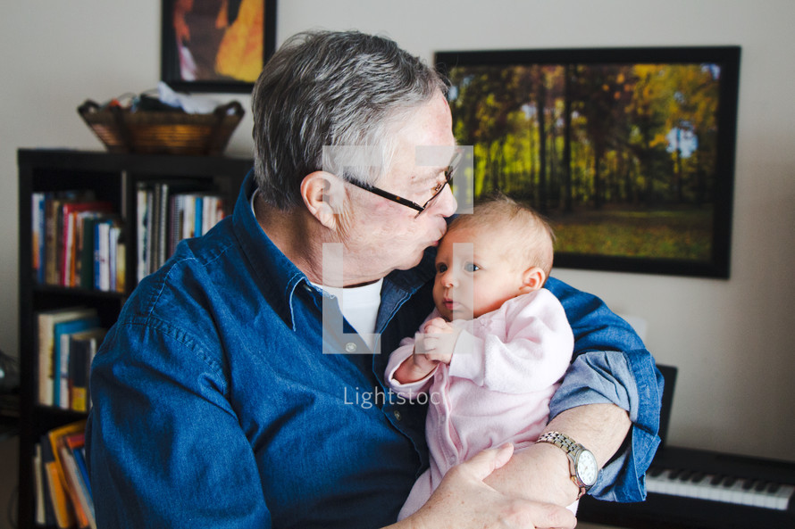 grandfather kissing his infant granddaughter 