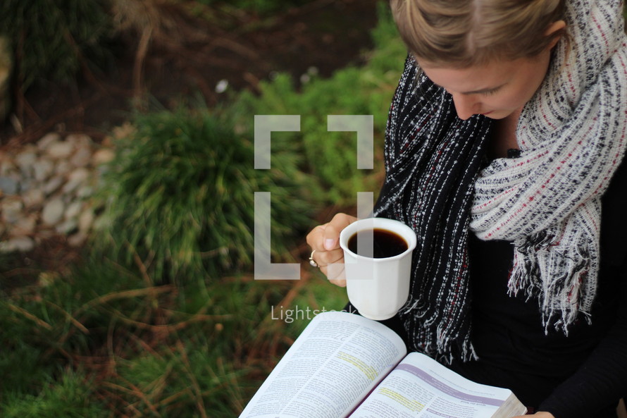 a woman reading a Bible and holding a mug 