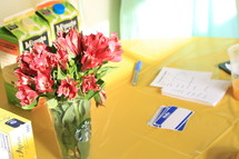 orange juice cartons, flowers in a Starbucks cup, name tags, pen and lists at a registration table  