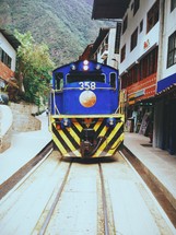 Train on railroad tracks travelling through a village.