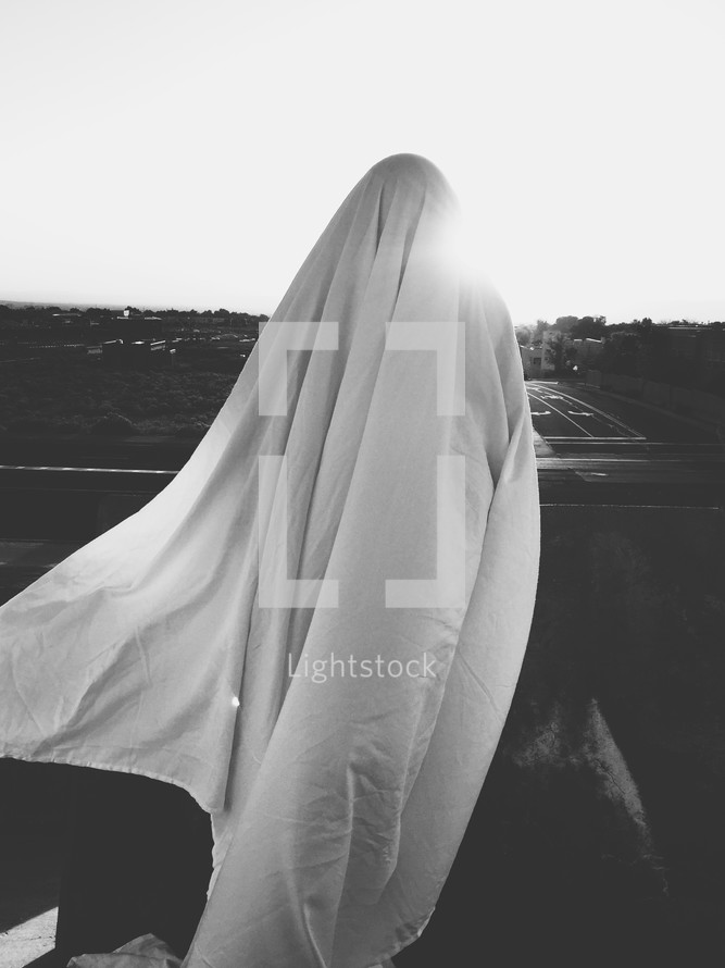 a woman under a white sheet outdoors 
