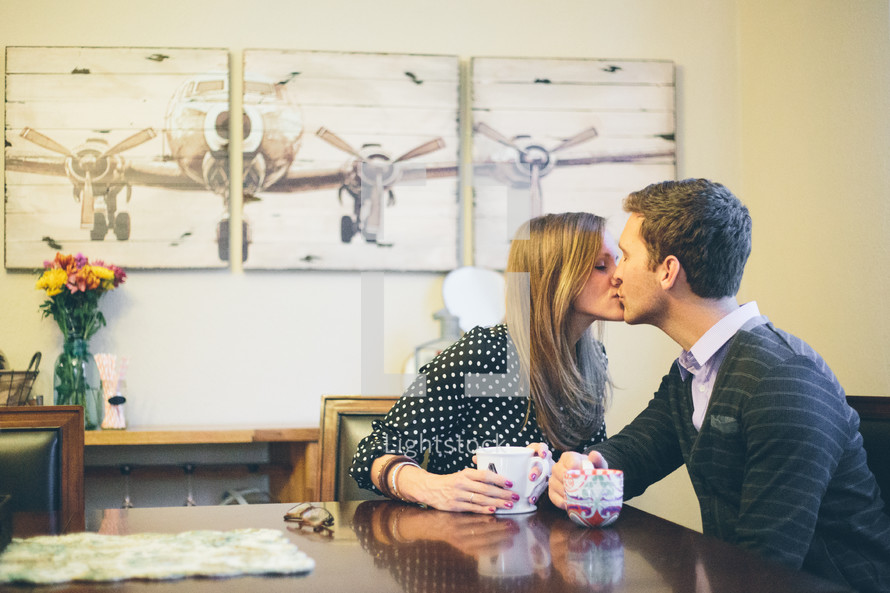 Couple kissing over coffee.