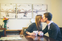 Couple kissing over coffee.
