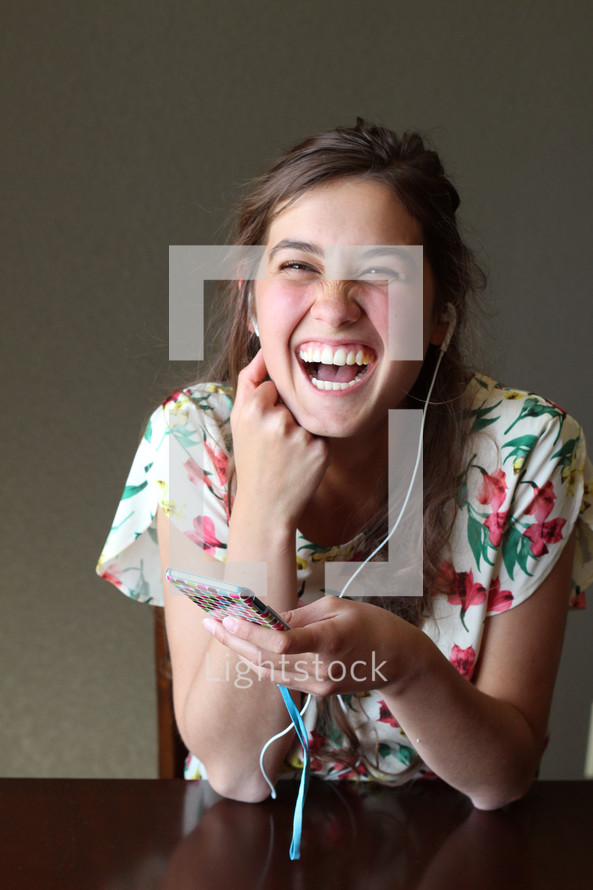 A girl listening on ear phones and laughing.