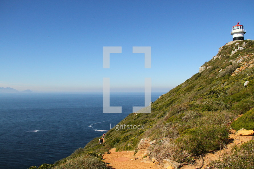 Lighthouse on a hilltop overlooking the ocean.