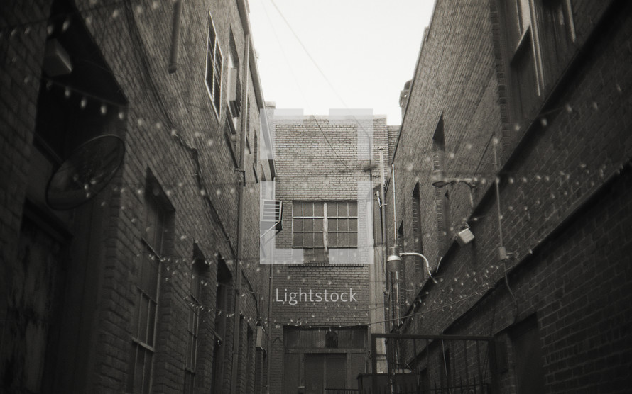 hanging strings of lights between brick buildings in an alley 