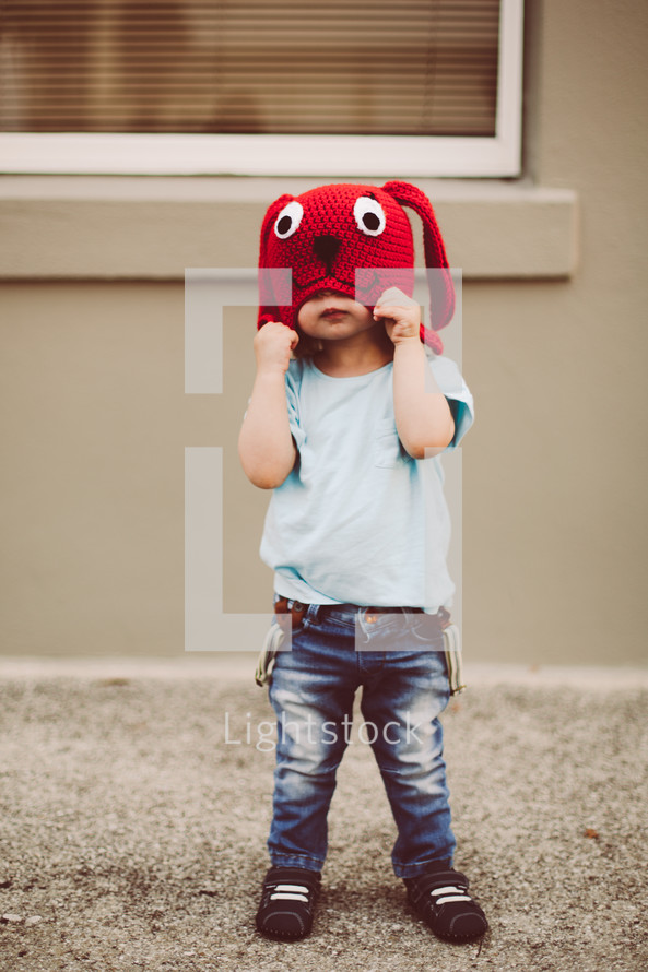 a toddler boy in a red knit dog hat 