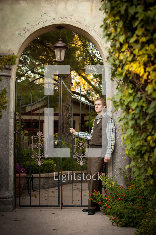 Young man standing in front of an ornate iron gate