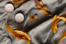 tea candles and fall leaves on a blanket 