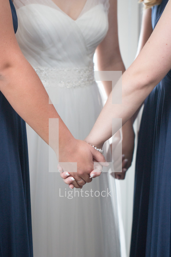 bride and bridesmaids holding hands in prayer 