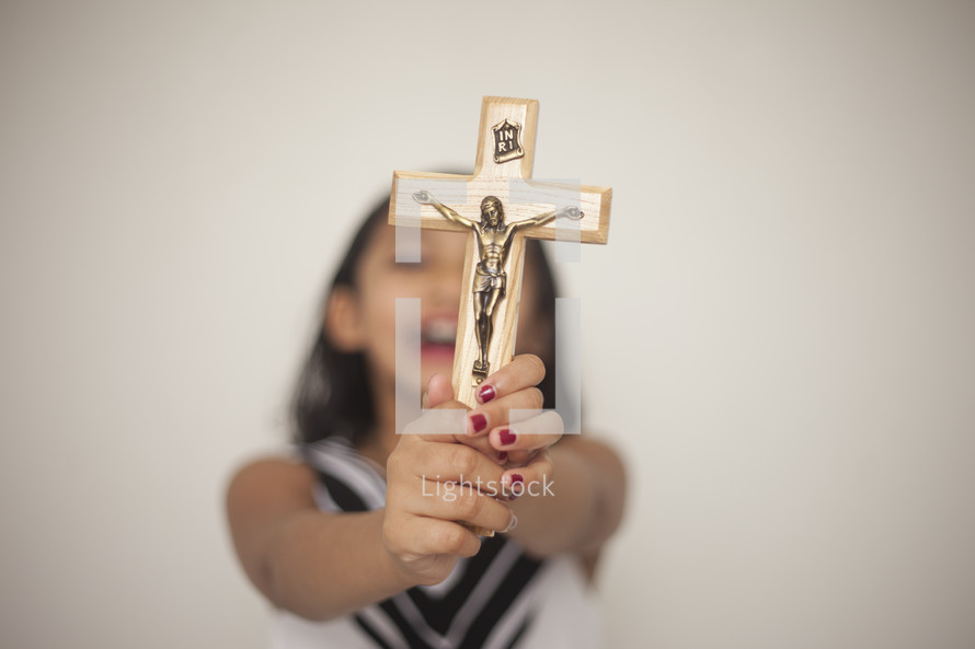 a young girl holding up a crucifix with joy