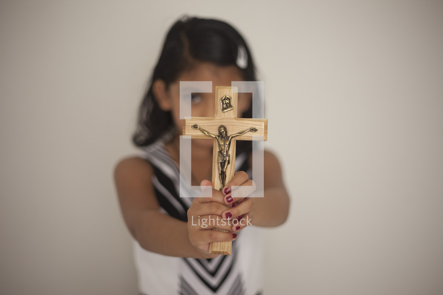 a girl holding up a crucifix 