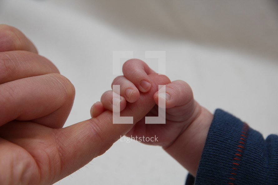 newborn holding a finger 